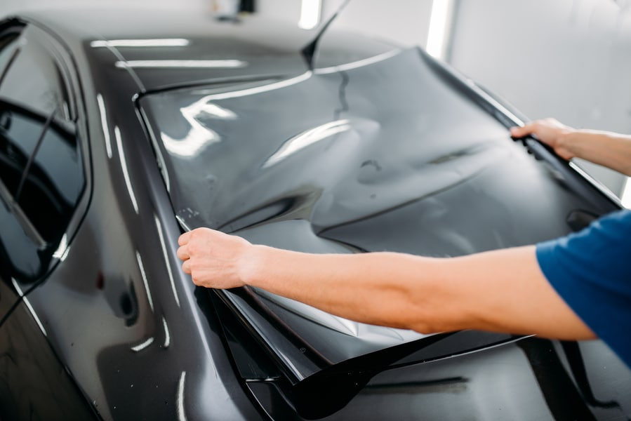 Male specialist with car tinting film in hands